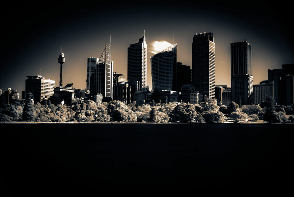 Panoramic black and white photograph of Sydney skyline against dramatic sky