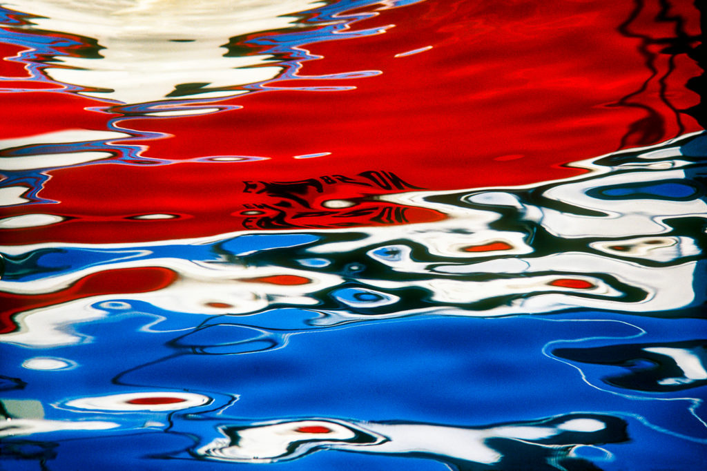 Abstract photograph of reflections, red white and blue from a boat